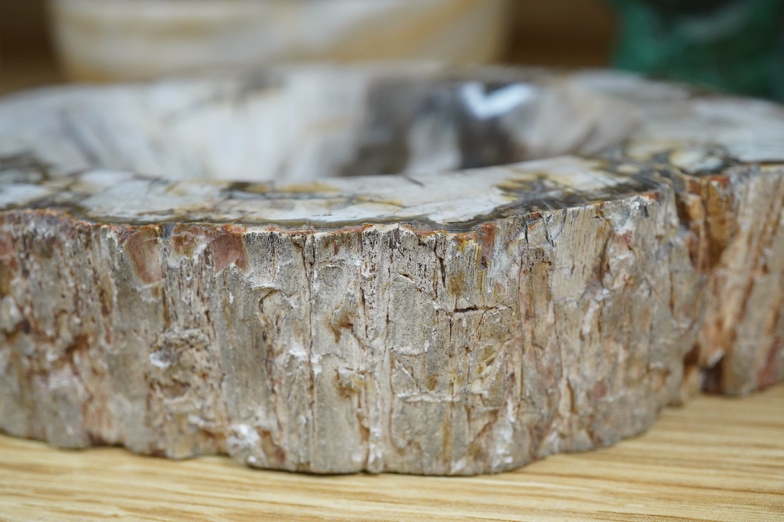 Two petrified wood ashtrays, a malachite rock, three onyx bowls, one with cover, and one other item, larger ashtray 17.5cm wide